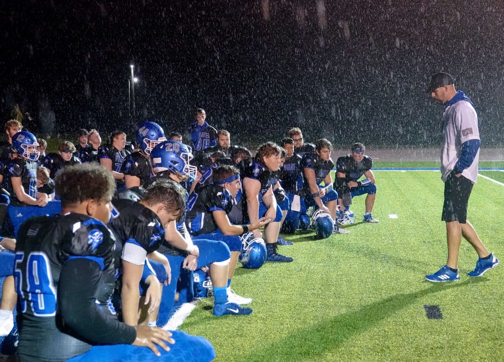 Boonville Pirates coach Greg Hough consoles the players after their rain-drenched defeat